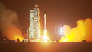 a rocket launches in the early morning hours above a plume of fire