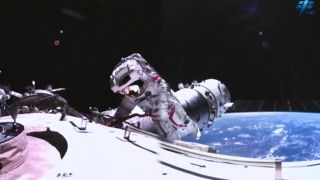 an astronaut in a spacesuit floats outside of a large white cylinder in space. earth can be seen in the background